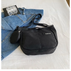 Detail of black canvas tote bag showing the fashion label and detachable round coin purse