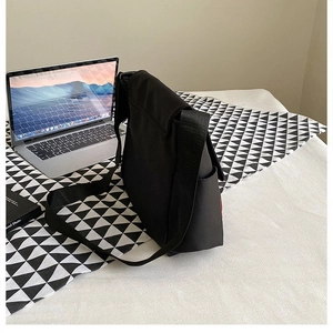 Dettaglio borsa a tracolla in tela nera con spazio per contenere un laptop
