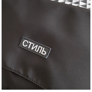 Dettaglio ravvicinato di una borsa in nylon nero con etichetta in gomma e testo cirillico