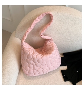 Detail of pink quilted tote bag with floral stitching on soft texture surface
