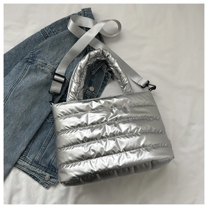 Detailed view of silver quilted nylon bag with detachable grey strap and blue denim jacket