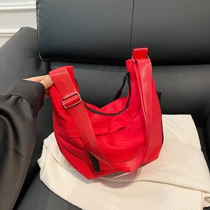 Détail du sac hobo en nylon rouge avec large bandoulière en tissu réglable et fermeture éclair