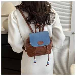 Detail of vintage mini backpack showing brown faux leather and blue denim patchwork design