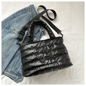 Close-up of black quilted puffer tote bag with nylon strap and metal hook details