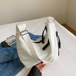 Détail du sac fourre-tout en nylon blanc montrant la bandoulière et le zip à nœud noir