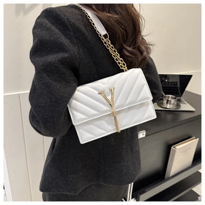 Sac bandoulière blanc matelassé avec détail en V doré et pompon porté à l'épaule
