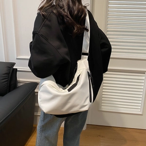 Gros plan d'un sac bandoulière en nylon blanc avec large sangle sur un mannequin