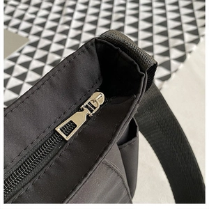Dettaglio della cerniera in metallo argento e cuciture robuste su questa borsa in nylon nero