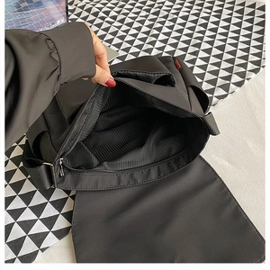 Dettaglio della borsa a tracolla in nylon nero con fodera a righe e scomparti interni