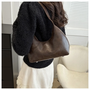 Détail d'un sac bandoulière en cuir vintage marron foncé avec clous argentés et logo
