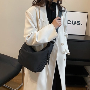 Détail du sac demi-lune en nylon noir avec bandoulière large porté par un mannequin