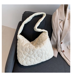 Detail of quilted floral pattern and wide shoulder strap on the cream white tote bag