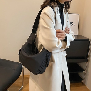 Détail d'un sac bandoulière en nylon noir en forme de croissant avec sangle réglable