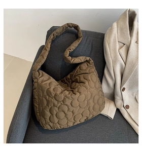 Macro shot of brown quilted tote bag showing intricate floral stitching and glossy nylon texture