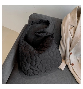 Detail of black quilted tote bag with unique 3D floral pattern on plush nylon fabric