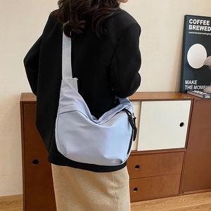 Détail du sac bandoulière croissant bleu clair avec large sangle porté par un mannequin