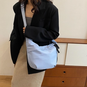 Détail de la bandoulière en nylon bleu clair avec tirette de fermeture noire sur modèle