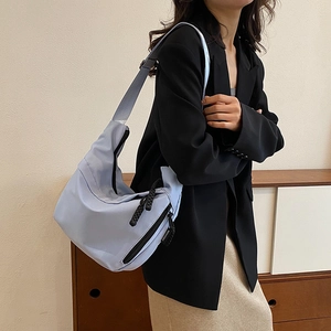 Détail du sac hobo bleu clair avec tirette tressée et étiquette de mode élégante