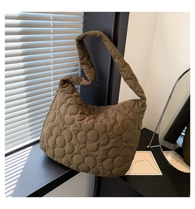 Detail of flower quilted texture on brown puffy tote bag with soft shoulder strap