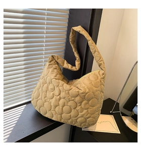 Detail of flower-shaped quilted pattern on khaki puffer tote bag under natural window light