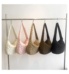 Five assorted colors of quilted puffer tote bags displayed on a sleek metal wall rack