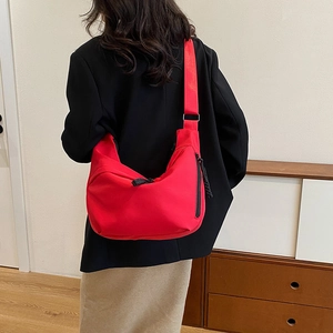 Détail d'un sac à bandoulière rouge vif avec bandoulière et fermetures éclair noires