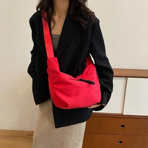 Détail du sac bandoulière rouge en demi-lune avec large sangle sur mannequin en blazer