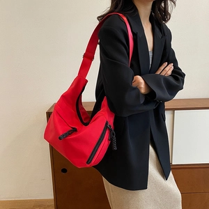 Détail du sac bandoulière en nylon rouge avec sangle réglable et poche zippée