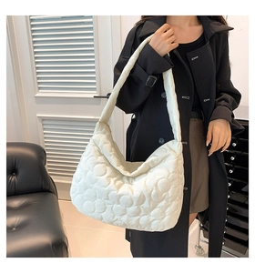 Detail of white quilted tote bag featuring floral stitching and wide shoulder straps