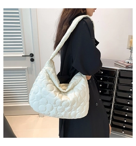 Detailed side view of white quilted tote bag with floral pattern on female model