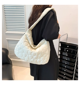 White quilted cloud tote bag with floral embossing worn by model on black coat