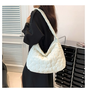 Detail of white quilted tote bag featuring 3D floral patterns and soft padded texture