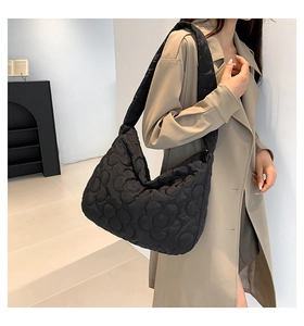 Detail of black quilted shoulder bag featuring elegant 3D floral stitching and wide strap