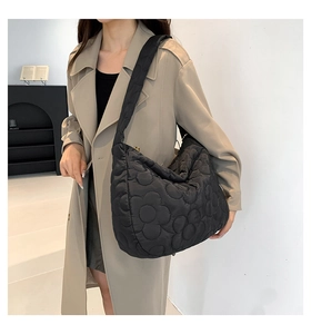 Detail of black quilted tote bag with floral pattern and wide shoulder strap