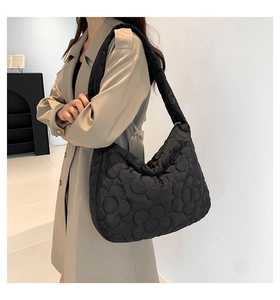 Quilted floral stitching detail on a black padded tote bag shown on a model