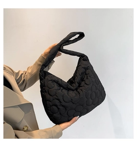 Close-up of black quilted puffer tote bag featuring floral pattern and wide shoulder strap