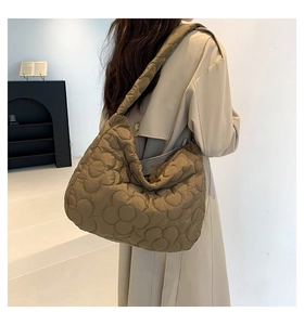Detail showing khaki quilted tote bag with floral stitching and padded shoulder strap