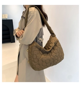 Detailed view of coffee quilted puff tote bag with floral pattern worn by a model