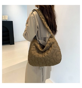 Brown quilted tote bag showing large capacity and soft texture on a shoulder model