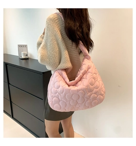Close-up of pink quilted tote bag with 3D floral texture and wide shoulder strap