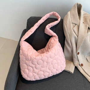 Pink quilted puffer tote bag with floral patterns on grey sofa with cream blazer
