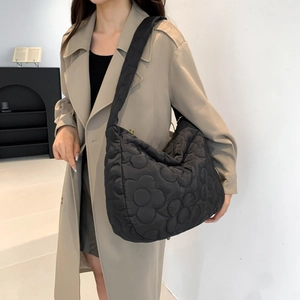 Large black quilted tote bag with floral puffer design and wide shoulder strap