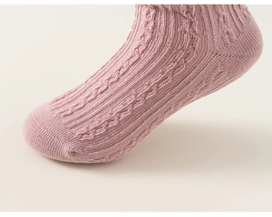 Macro detail of girls soft light pink cable knit cotton socks with ribbed texture