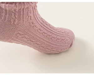 Detailed macro view of cable-knit texture and soft pink fabric on girl's cotton socks