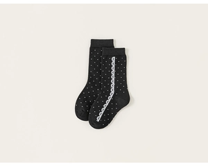Detail of girls' black knee-high socks with white polka dots and sweet lace trim