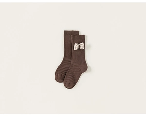 Detail view of dark brown ribbed kids socks with white polka dot bow on clean background