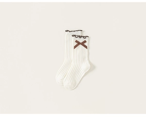 Detail of cream ribbed cotton kids sock featuring a brown polka dot bow and ruffled trim