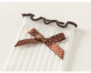 Detailed macro view of white ribbed cotton kids socks with brown bow and ruffle edge