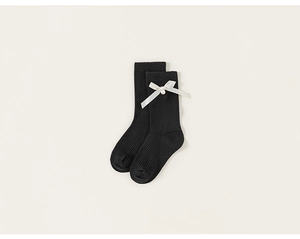 Detail of black ribbed knit girls' socks featuring white satin bows and pearl accents