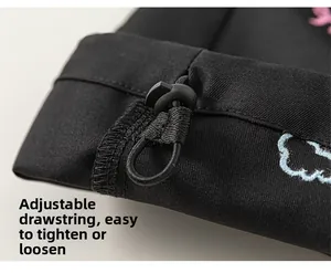 Détail du pantalon cargo montrant le cordon de serrage et le motif brodé de nuages